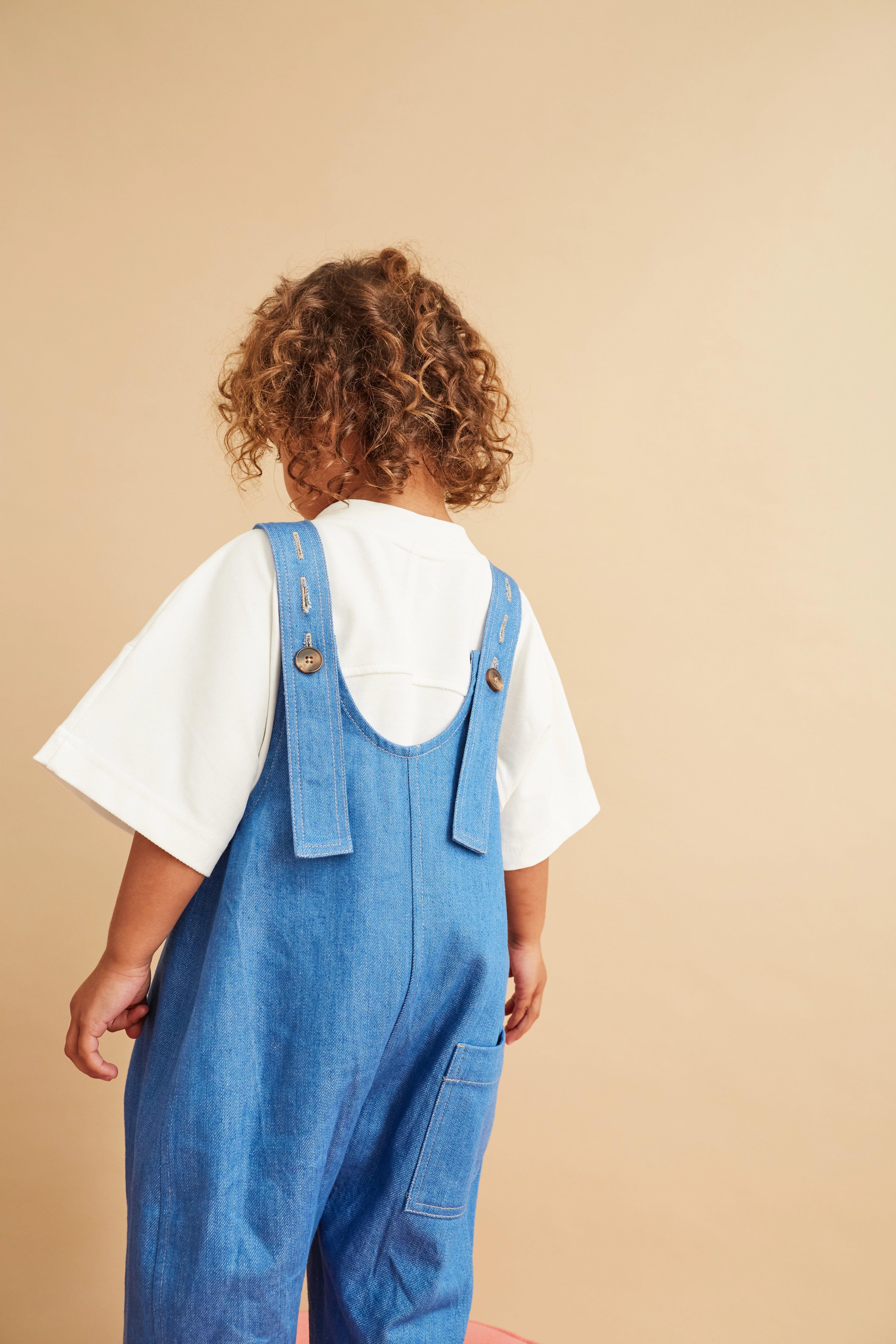 Kai denim is available for pre-order. Ready to post in 7 days Kai is the ultimate go-to for effortless cool. These oversized wide-leg denim dungarees have a relaxed, rounded fit with playful curved seams that bring a new twist to a classic. The front patch pocket adds a utility edge, and additional side seam pockets for all the little treasures. Kai has an adjustable strap fastening at the back meaning they grow with your kid, making it a wardrobe staple that can last several years. Crafted from 100% organic cotton denim and produced in the UK, these dungarees are sustainable as well as stylish. Proudly featured in Sunday Times Style. Studio Koter is a UK-based kidswear shop creating modern pieces for children and toddlers, with each garment produced sustainably in the UK and Portugal.