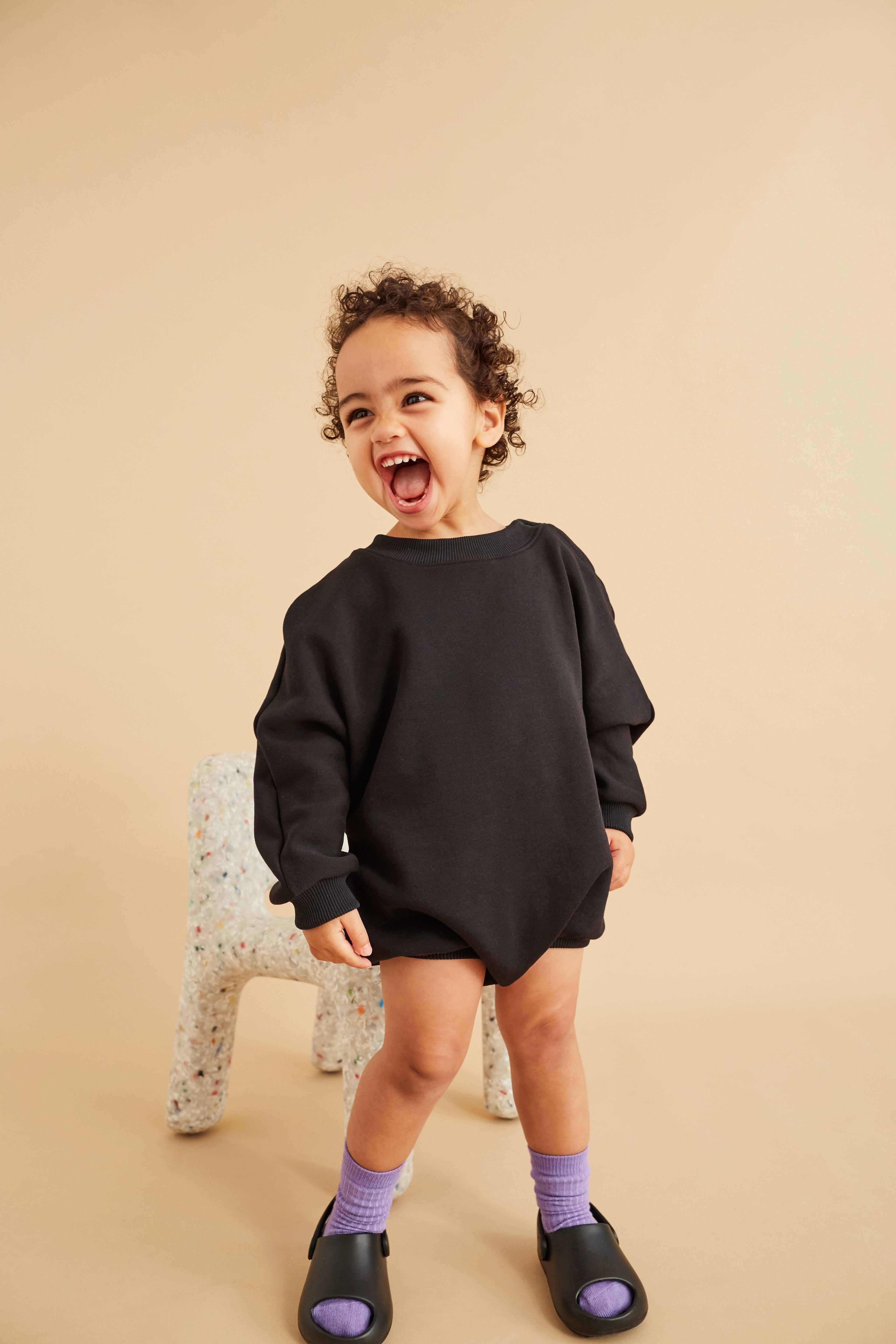 Rounded, oversized sweatshirt romper made from an organic cotton jersey sweatshirt-quality with a soft, brushed back. Circle seam-detail in back. Elasticated cuffs and press-buttons around crotch and neck. Wear on its own, with tights or with our Manu trousers on top. This is an oversized fit so plenty of room to grow into. 100% organic cotton Studio Koter is a UK based unisex kidswear and toddler clothing brand. All garments are produced in the UK and Portugal in a considered and sustainable way.