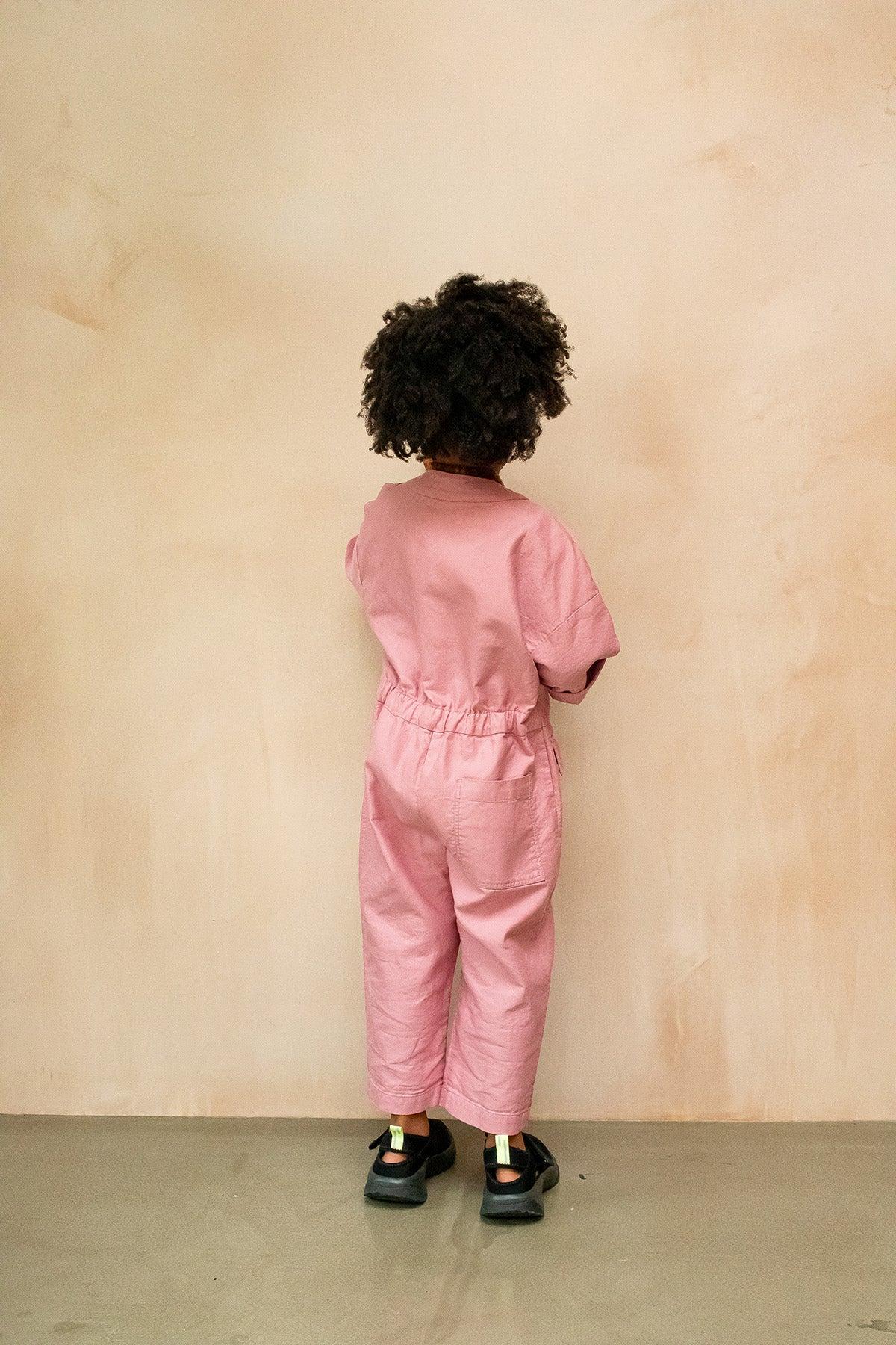 The Rae Boiler Suit is one of our must have items. Made from soft and durable double-face organic cotton in a dusty pink tone, this boiler suit is perfect for an easy outfit-in-one. The Rae overalls have an oversized fit and a lengthened sleeve for autumn. With patch pockets and a zip front, it has been designed for easy dressing and functionality. The unisex design makes it versatile, ideal for layering and everyday wear. Key Features: Made from 100% organic cotton Unisex design Zip front for easy dressing Adjustable waistband to pull-in the back Spacious pockets for storing tiny treasures Ideal for layering in cooler weather Studio Koter is a modern, unisex, functional kidswear shop designed in the UK and made sustainably in the UK and Portugal.